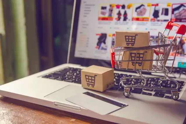 Shopping online concept - Parcel or Paper cartons with a shopping cart logo in a trolley on a laptop keyboard.